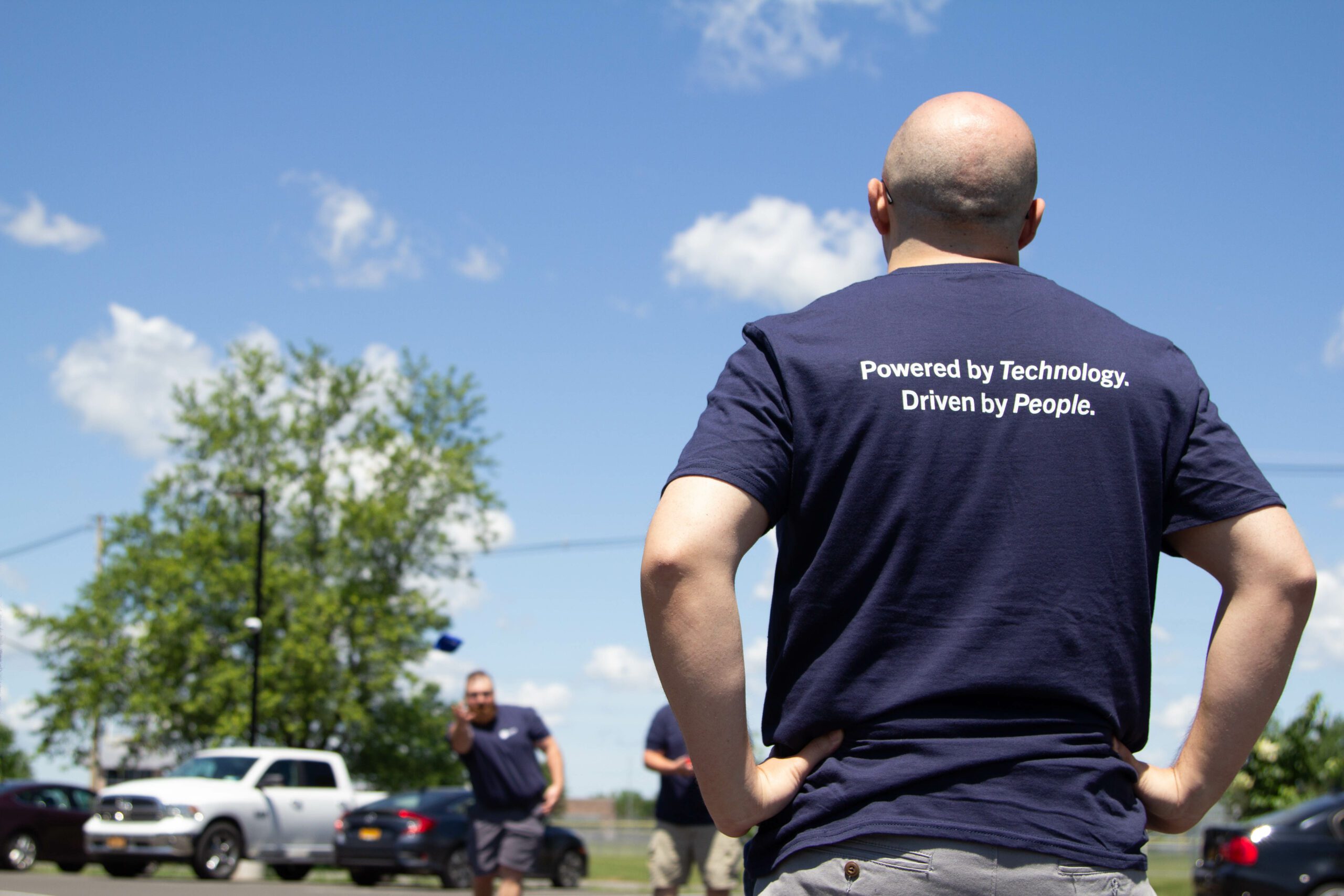 The back of a security analyst at M.A. Polce IT and Cybersecurity with a t-shirt that reads "Powered by People. Driven by Technology" to promote the MSP/MSSP company