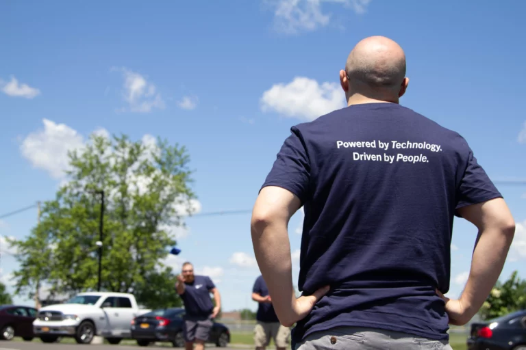 The back of a cybersecurity analyst at M.A. Polce looking towrds the sky. The back of his graphic T reads "Powered by Technology Driven By People."